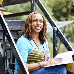 Carer Jaycee sitting on steps with notebook